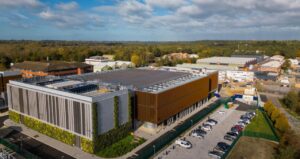 Image of Nebius AI factory in the UK surrounded by a parking lot and green foliage.
